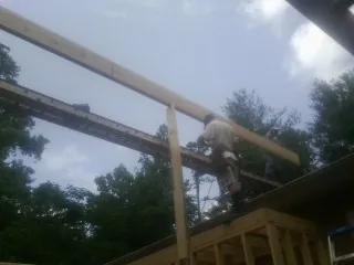 Carpenter setting a ridge beam over a new addition frame — Ice Dam Removal by Roofing Brothers in Calimesa