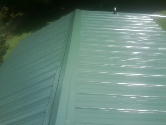 New green metal panels meeting at the ridge of a roof — Flat Roof Repair work by our crew in Calimesa