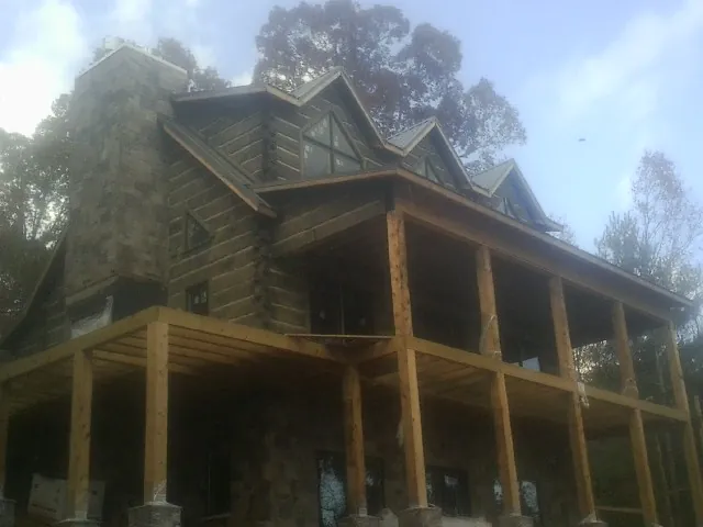 Stone chimney and dormers on a large log home with a timber porch in Calimesa
