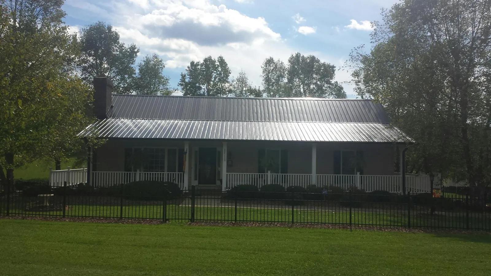 Gray metal roof on a brick ranch with a full width front porch — Gutter Guard Installation work by our crew in Calimesa