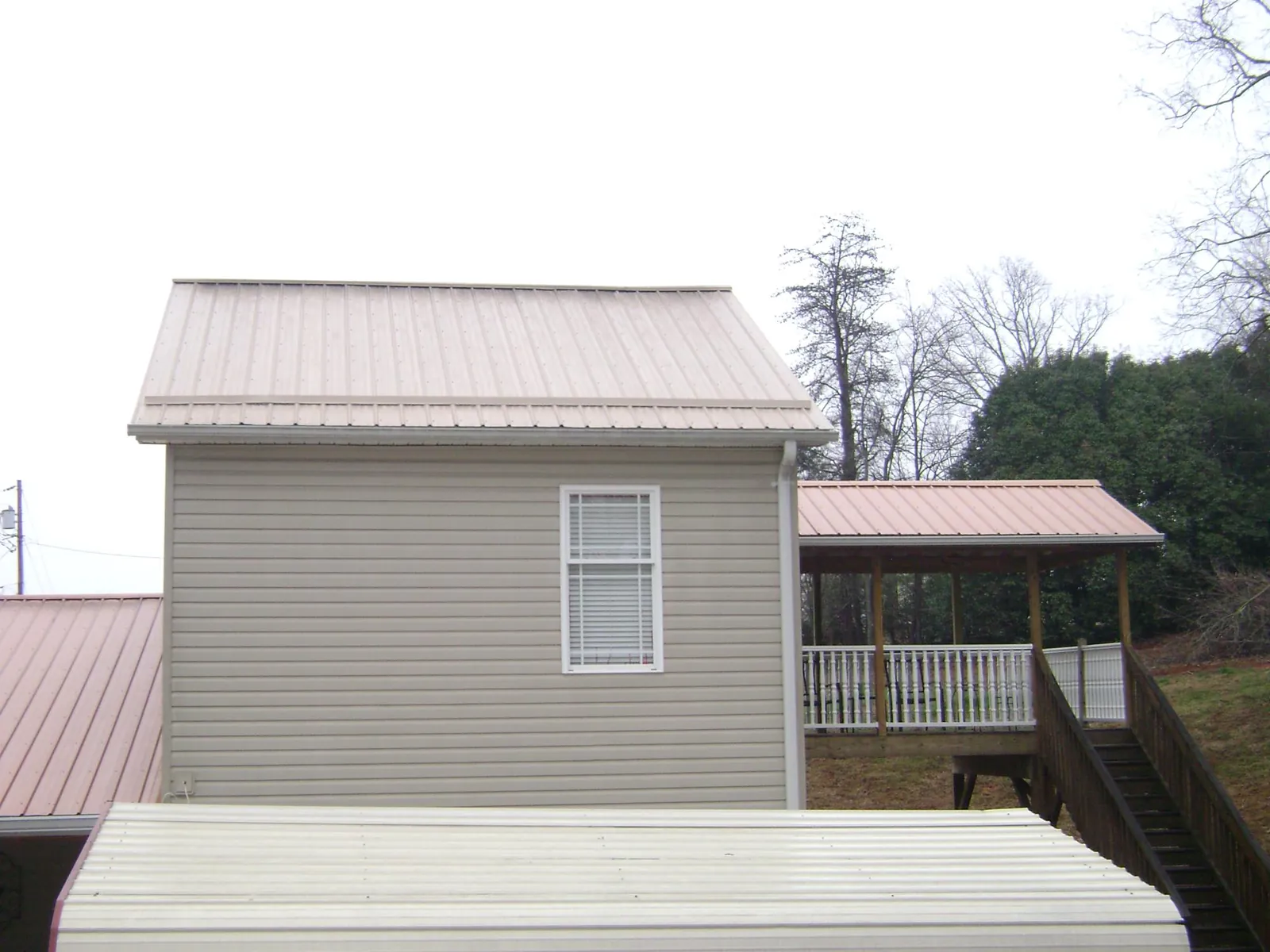 Tan metal roofs on a two story addition and attached porch, from a Roof Replacement job in Calimesa